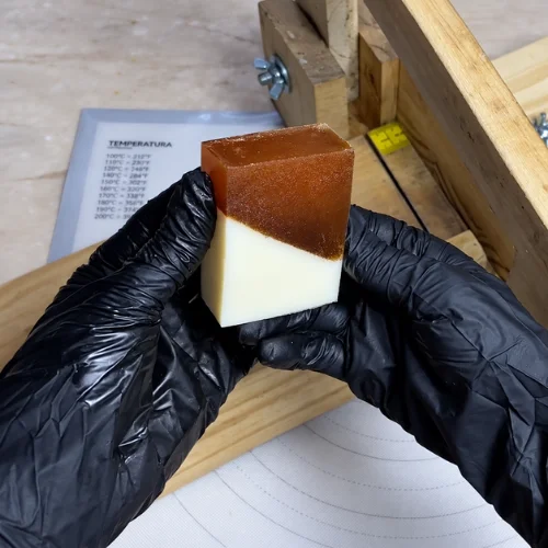 Sabonete bicolor com camada marrom e camada creme, nas mãos